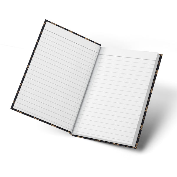 Open notebook with lined pages and a black cover featuring a gold floral pattern.