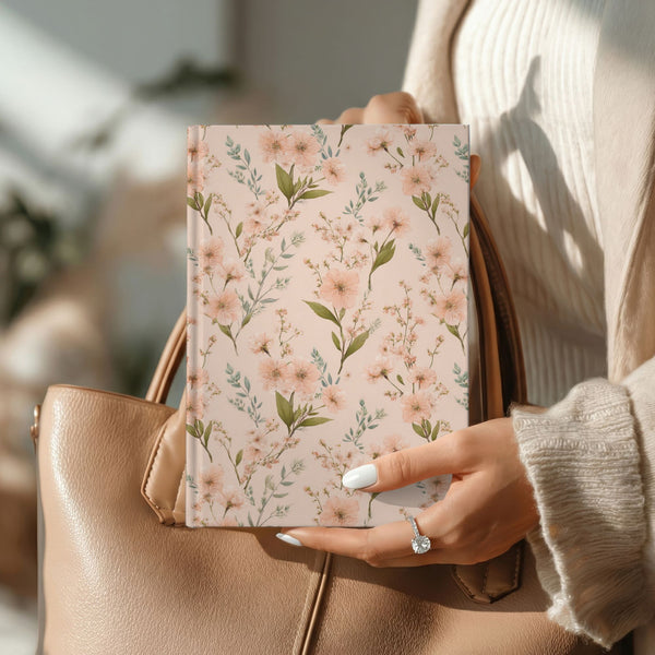 A5 grandmacore journal with a blush-pink cover, dense peach and blush blossoms, and sage-green leaves