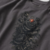 A close-up of a dark gray crewneck t-shirt featuring a detailed graphic print of black roses and a small red ladybug on the front.
