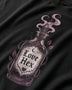 Close-up of a black t-shirt featuring a detailed graphic of a glass potion bottle labeled 'Love Hex' with purple smoke and leaves.