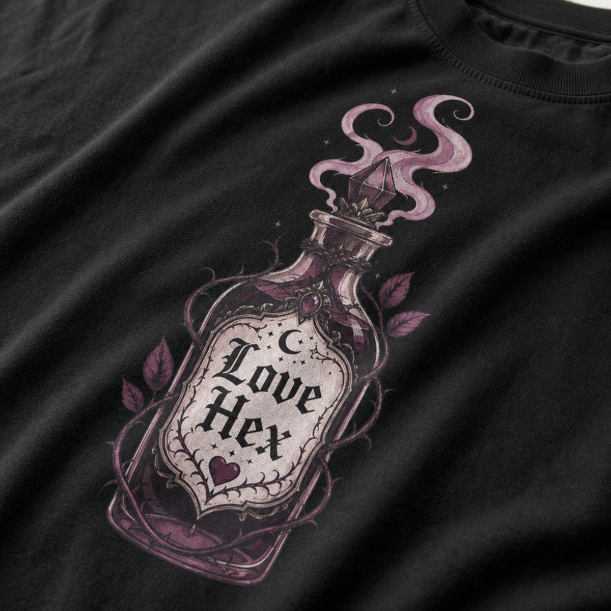 Close-up of a black t-shirt featuring a detailed graphic of a glass potion bottle labeled 'Love Hex' with purple smoke and leaves.