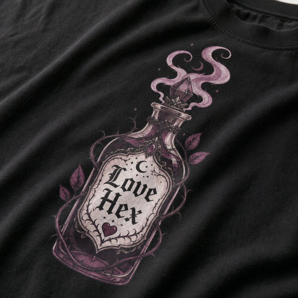 Close-up of a black t-shirt featuring a detailed graphic of a glass potion bottle labeled 'Love Hex' with purple smoke and leaves.