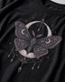 A close-up of a black t-shirt featuring a detailed gothic graphic of a moth with crescent moons and stars.