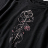Close-up of a black crewneck t-shirt featuring a detailed graphic print of an ornate key wrapped in a dark ribbon with a pink rose and leaves.
