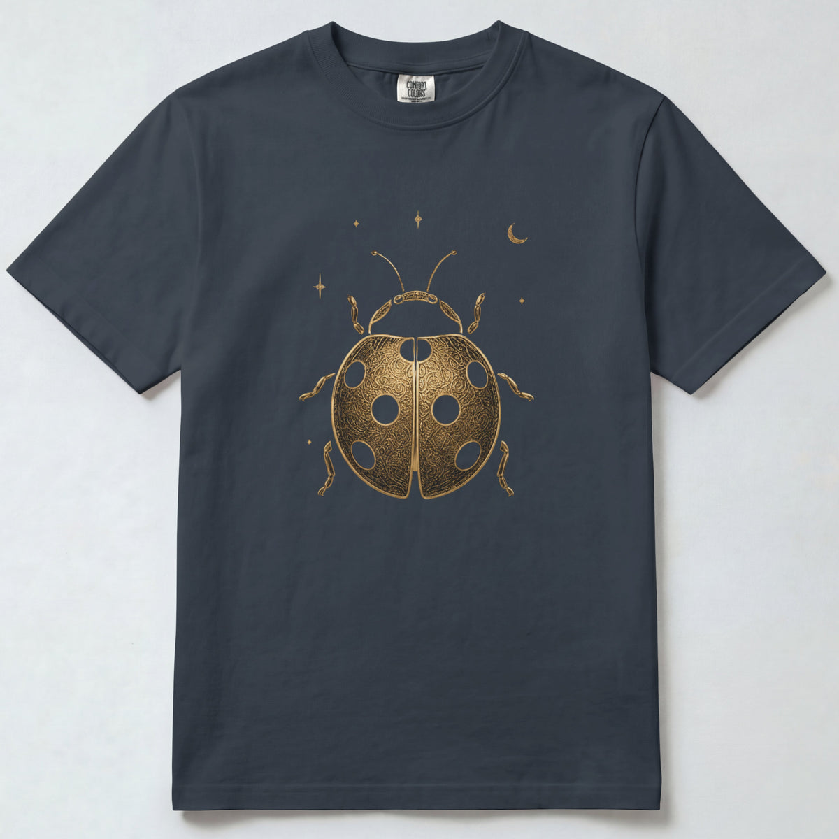 A dark charcoal gray short-sleeve t-shirt with a metallic gold ladybug graphic and small stars and crescent moon on the front, displayed flat against a light gray background.