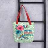 Tote bag with floral design and text 'Inspire. Educate. Motivate.' hanging on a black metal rack.