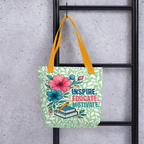 Tote bag with floral design and text 'Inspire. Educate. Motivate.' hanging on a black metal rack against a concrete wall.