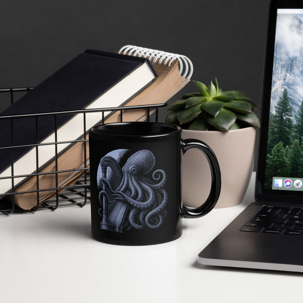 Black mug with octopus design on a desk with laptop, books, and plant