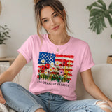 Woman wearing a pink t-shirt with a colorful graphic design sitting on a couch. 