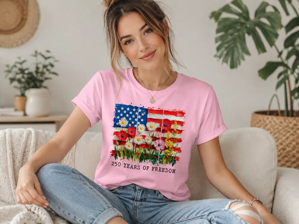 Woman wearing a pink t-shirt with a colorful graphic design sitting on a couch. 