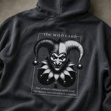 Black hoodie with a graphic design of a jester's face and text on a plain background 
