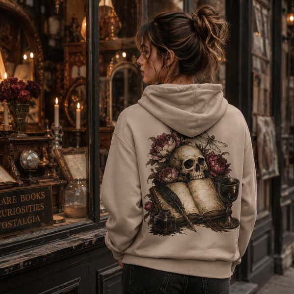 Person wearing a hoodie with a skull and floral design in front of an antique shop window.