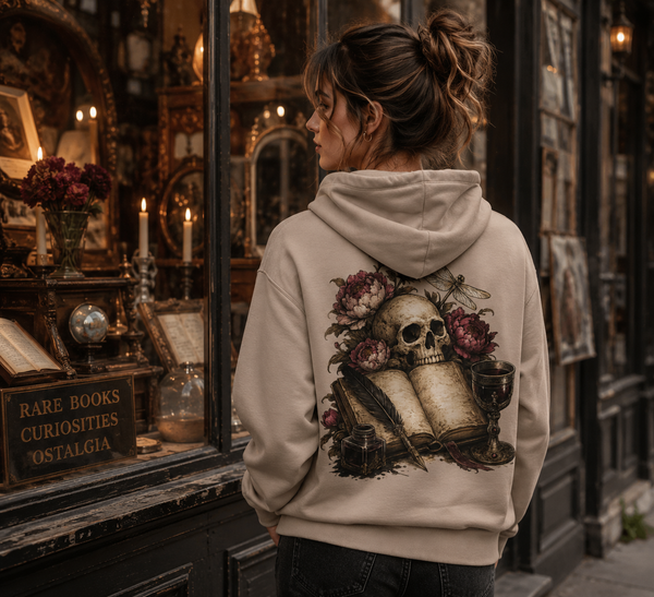 Person wearing a hoodie with a skull and floral design in front of an antique shop window.