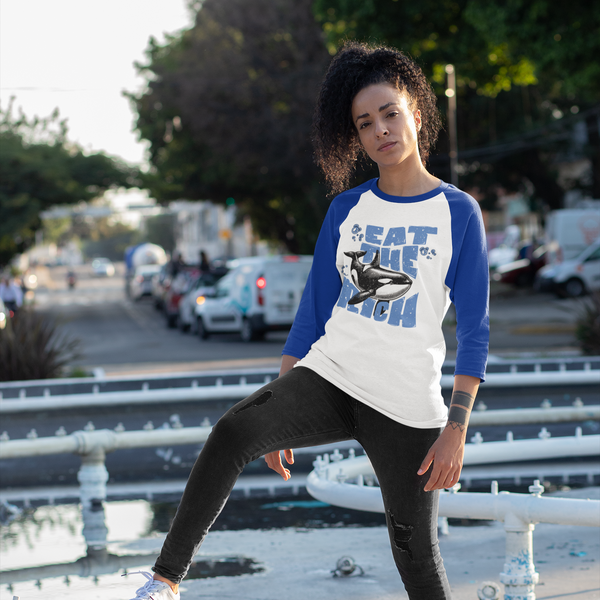 Person wearing a white and blue baseball shirt with a graphic design, standing on a street.