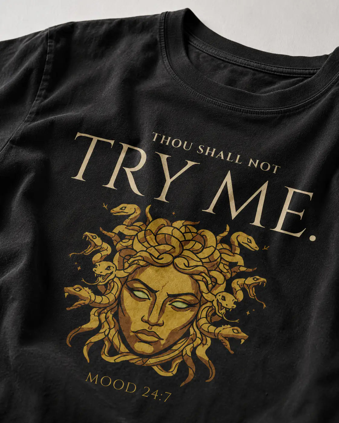 Black t-shirt with gold graphic and text 'Thou shall not try me' on a plain background 