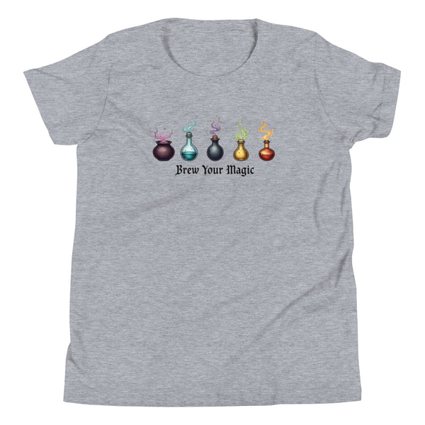 A grey youth staple t-shirt displaying a graphic of five different colored potion bottles, each emitting a wisp of colored smoke. Below the bottles, the text "Brew Your Magic" is written in a dark, stylized font.