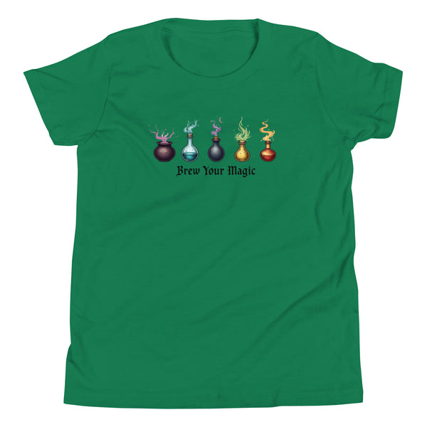 A green youth staple t-shirt displaying a graphic of five different colored potion bottles, each emitting a wisp of colored smoke. Below the bottles, the text "Brew Your Magic" is written in a dark, stylized font.
